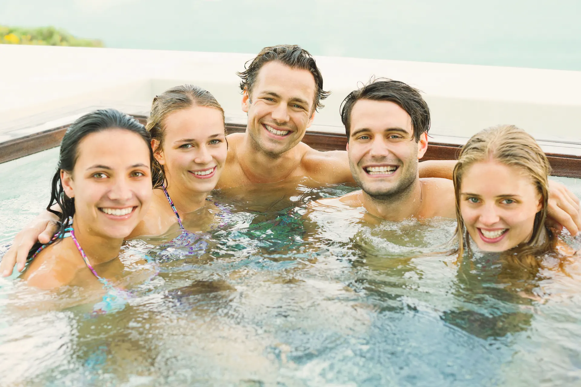 Five friends relaxing together in a Courtyard hot tub on a bright day